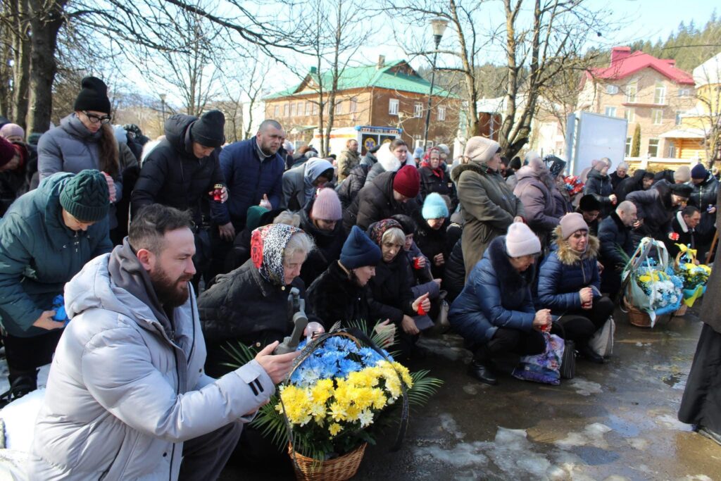 Люди коліна, тримають квіти, вшанування пам'яті