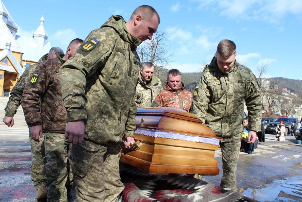 Військові несуть дерев'яну труну на вулиці