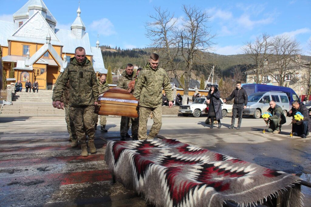 Українські військові несуть труну біля церкви