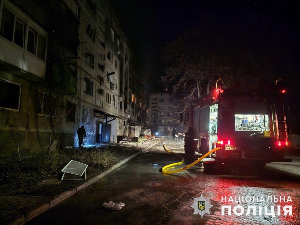 Пожежник на нічній вулиці біля пожежного автомобіля.