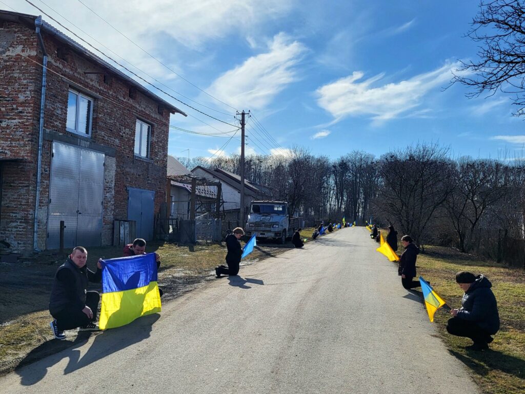 Люди із українськими прапорами вздовж дороги