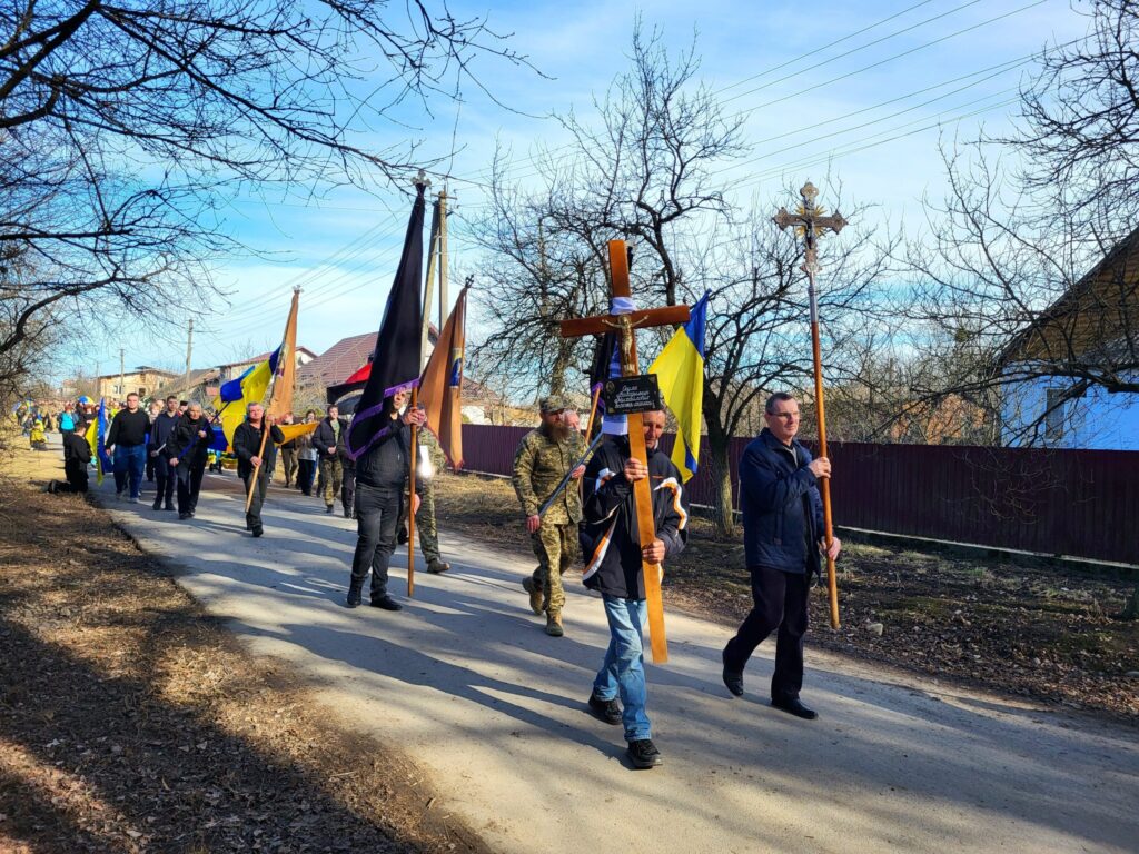 Хода людей з прапорами і хрестами на вулиці.