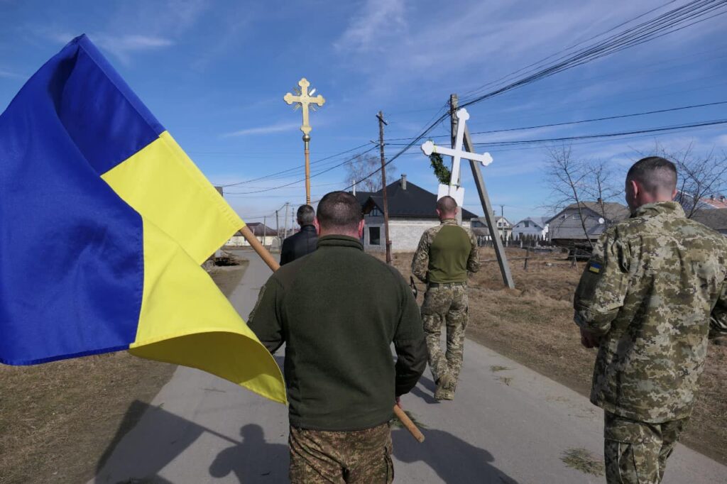 Українські військові з прапором та хрестами на вулиці.