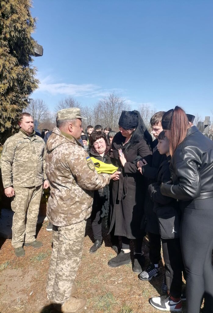 Військовий передає прапор родині на церемонії.