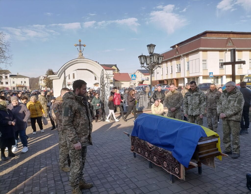 Похоронна процесія військовослужбовця з труною, накритою прапором