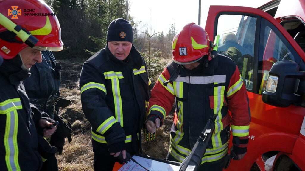 Пожежники обговорюють план дій біля автомобіля