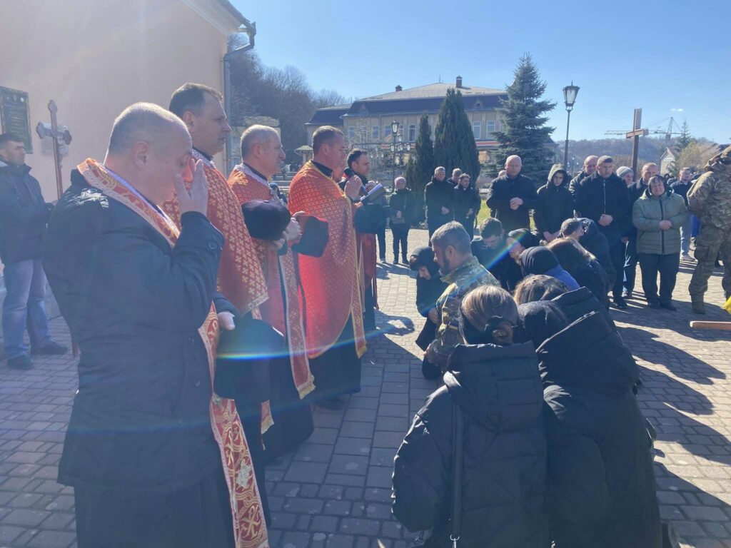 Люди моляться перед священиками на вулиці.