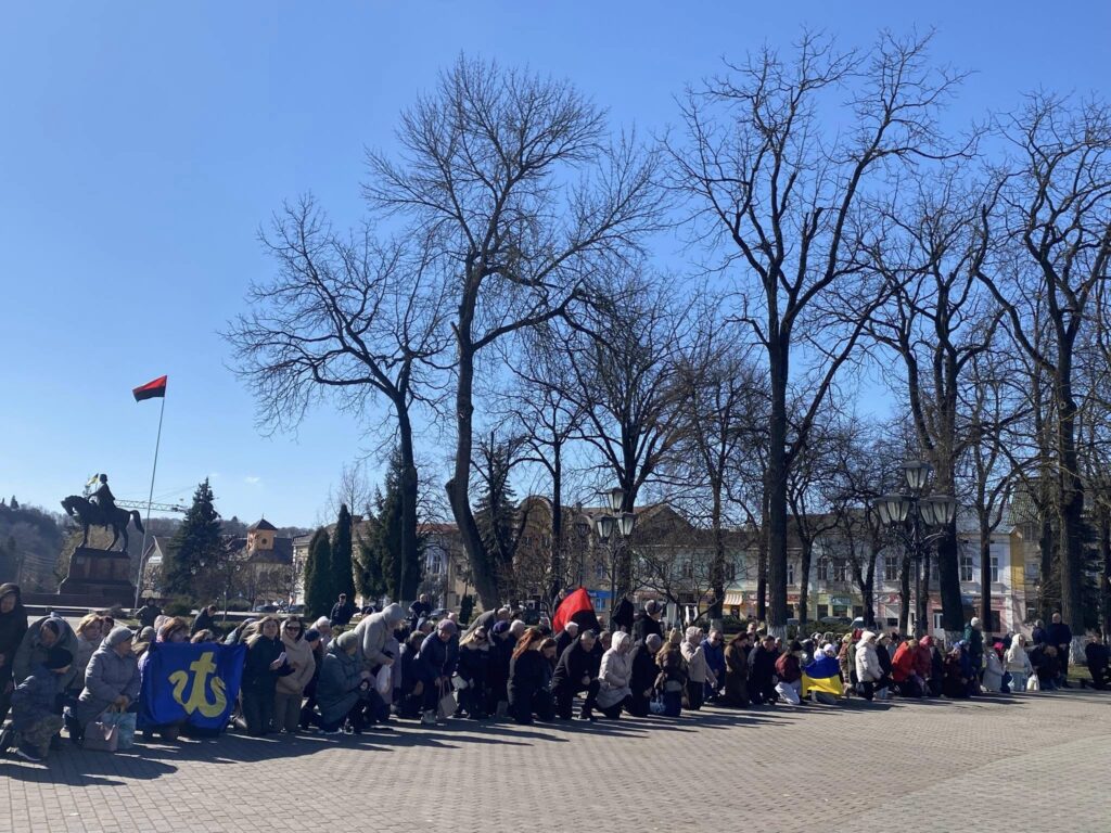 Люди в парку з прапорами України, чорним стягом.