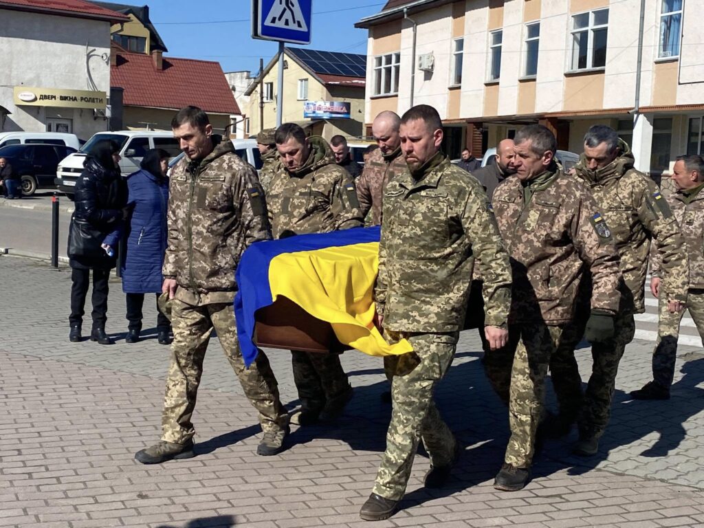 Військовослужбовці несуть труну з прапором України.