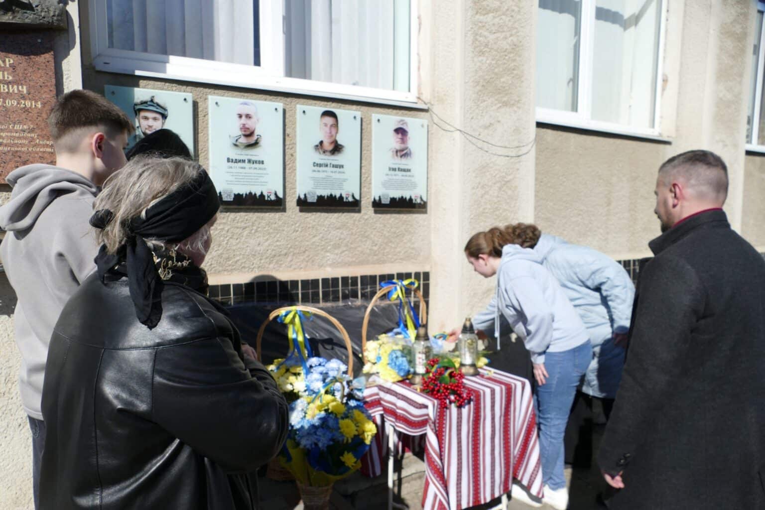 Люди вшановують пам'ять героїв біля меморіалу.