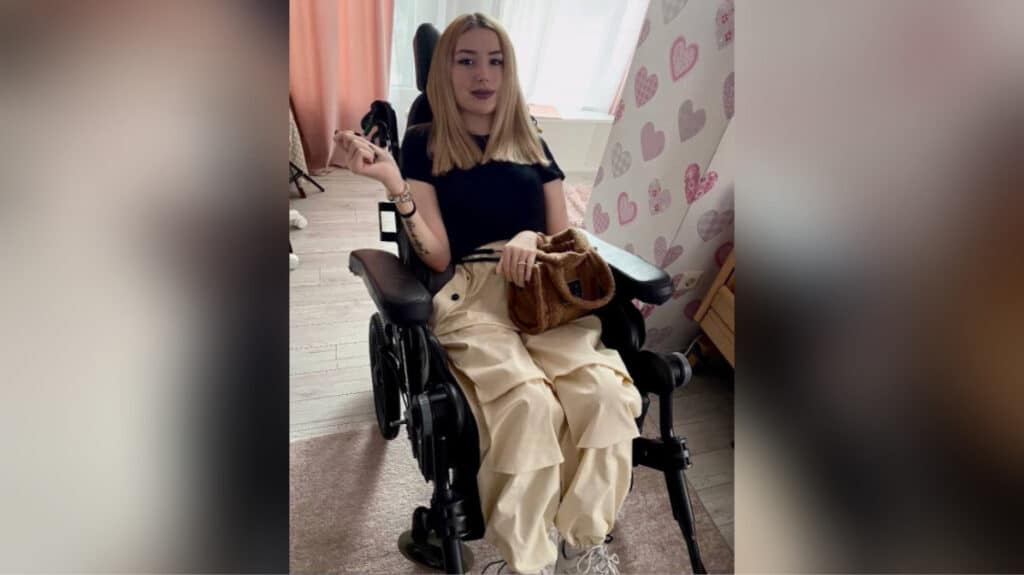 Жінка в інвалідному візку вдома з сумкою