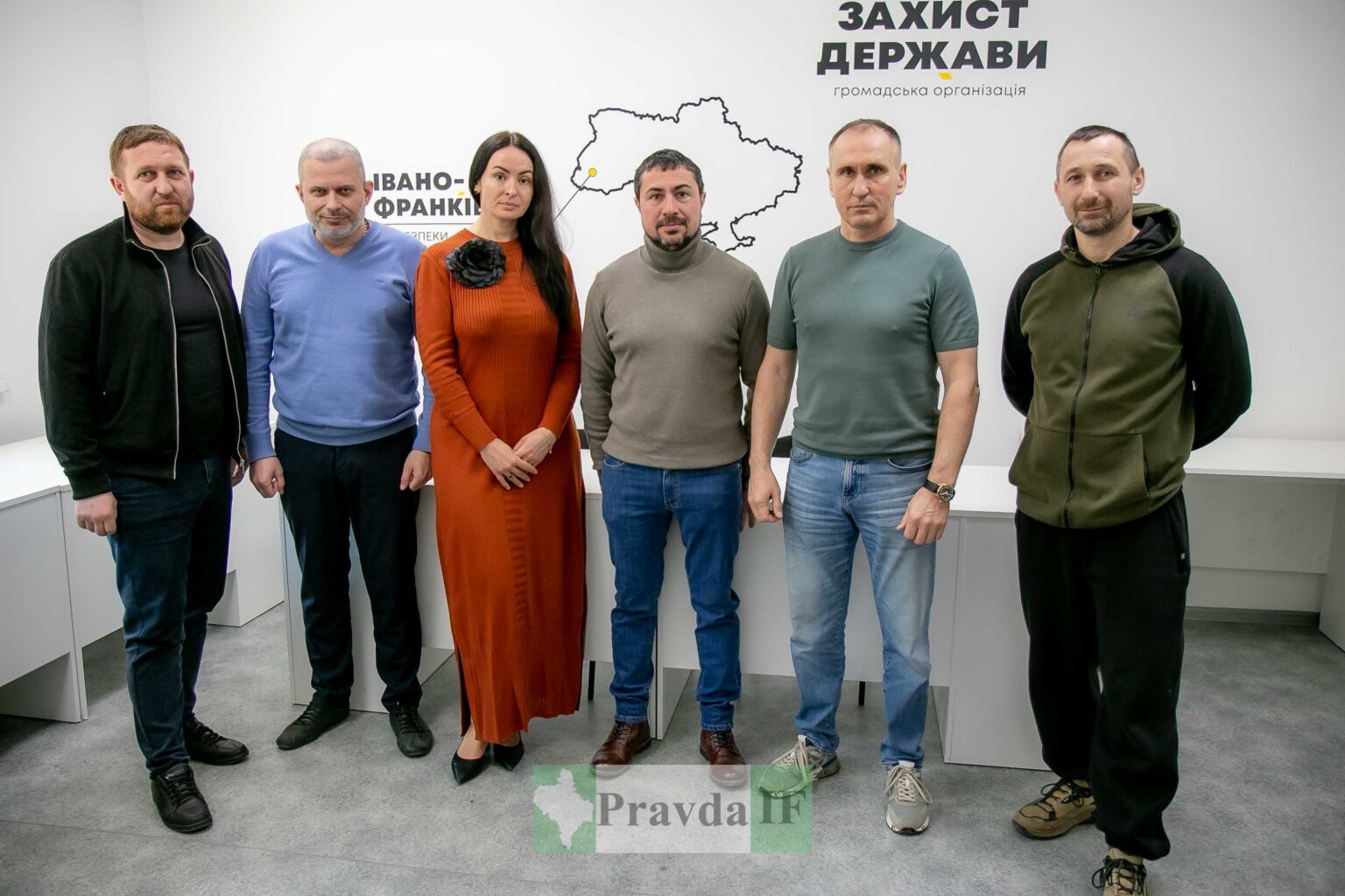 Групове фото людей на фоні логотипу організації