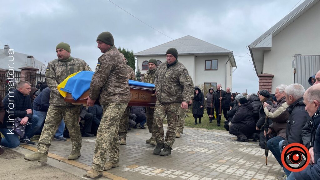 Військові несуть труну з прапором України.