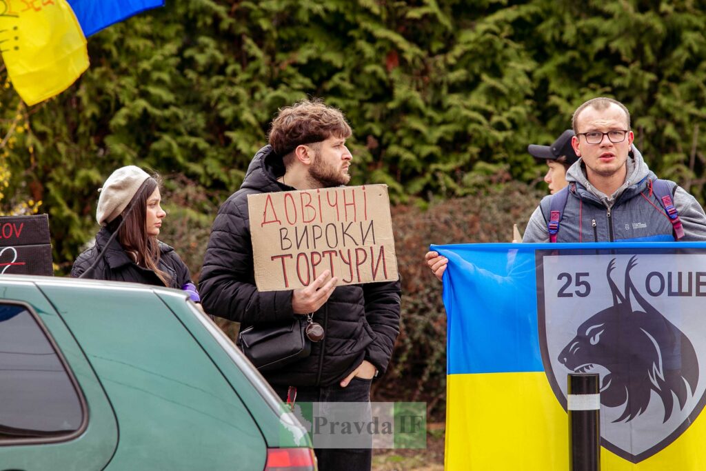 Протестувальники з плакатами та українським прапором