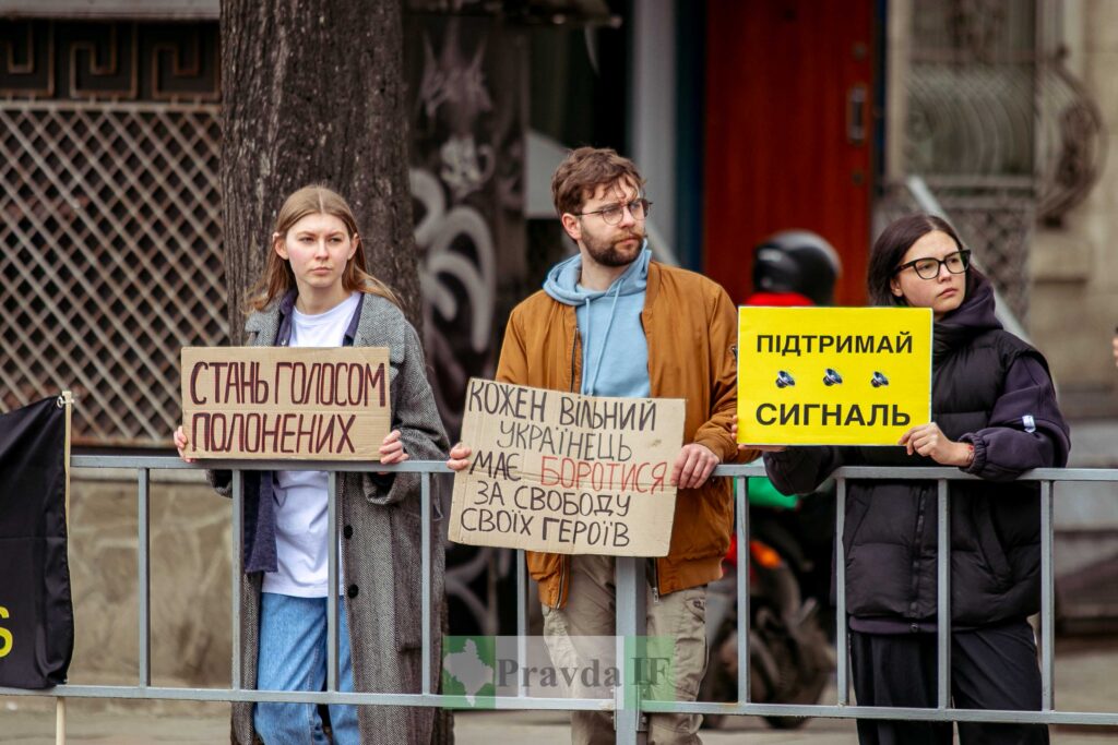 Люди з плакатами на мітингу в Україні.