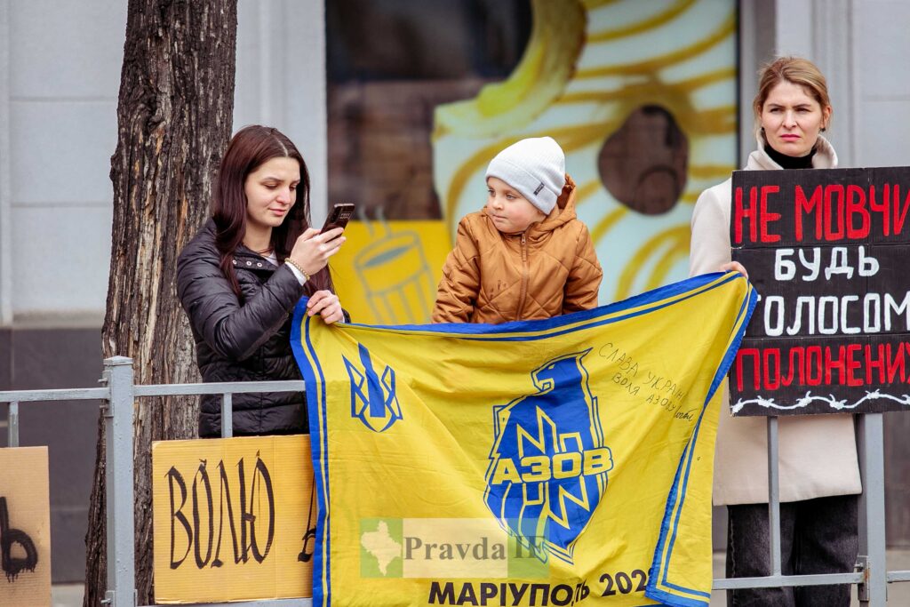 Жінки і дитина тримають українські прапори на акції.