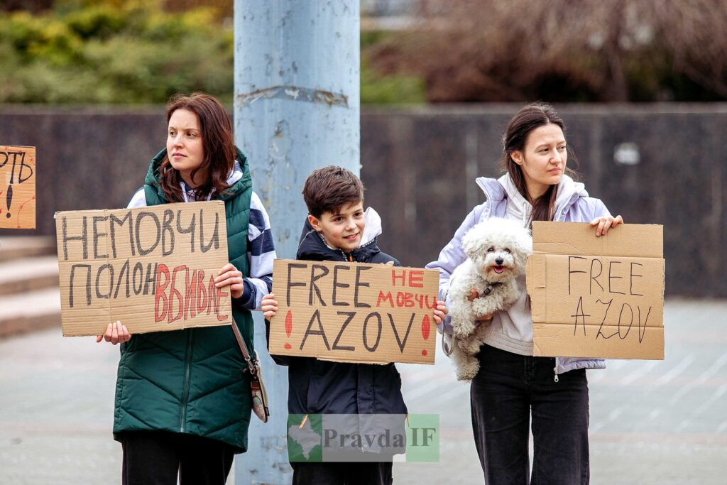 Люди тримають плакати на протесті з написами.