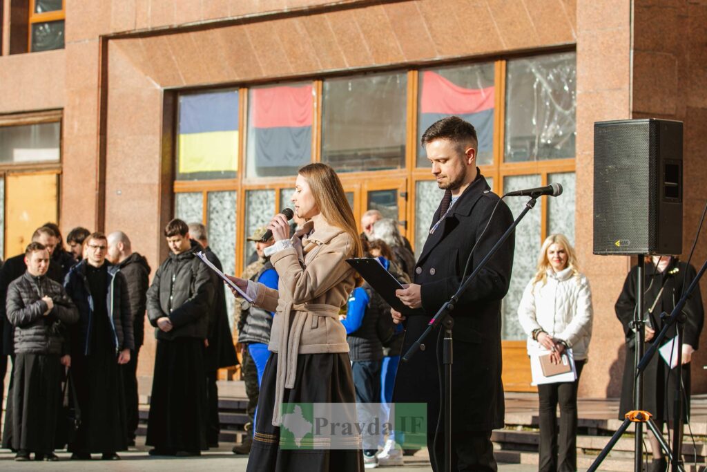 Вуличний виступ перед будівлею з прапорами.