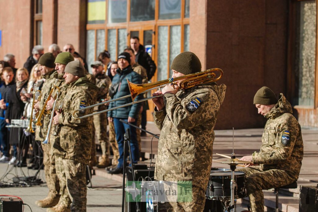 Військовий оркестр виступає на вулиці перед публікою.