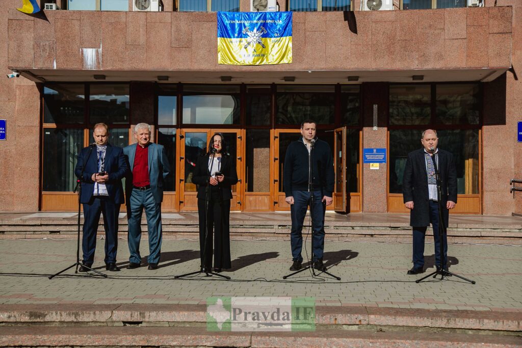 Люди на пресконференції під українським прапором.