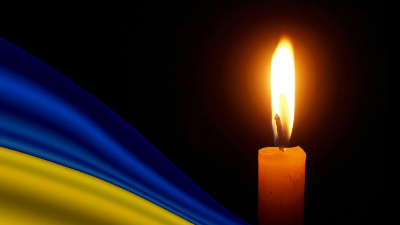 Свічка на фоні українського прапора