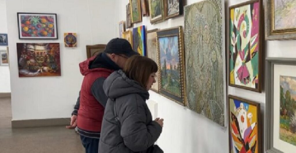 Люди оглядають картини в галереї