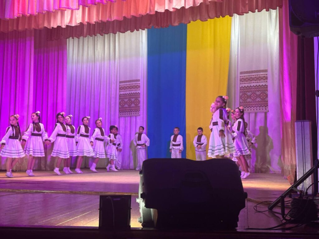 Діти у національному вбранні на сцені з прапором