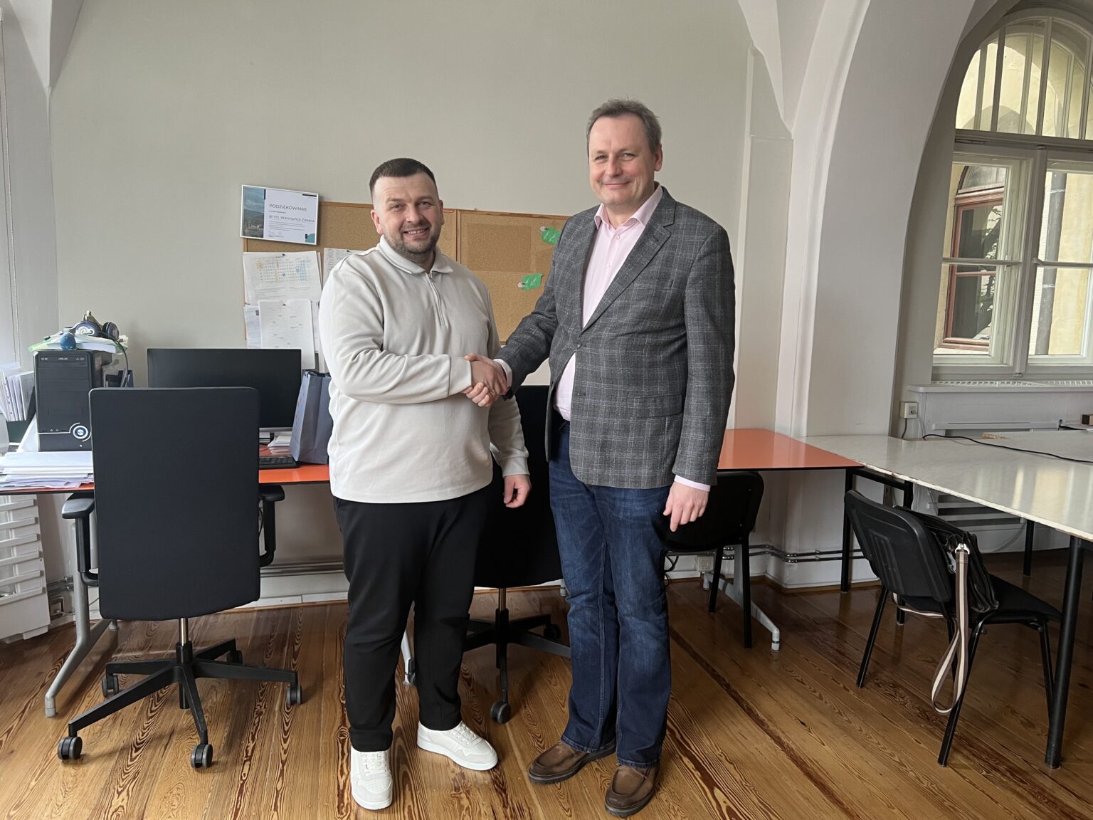 Двоє чоловіків потискають руки в офісі