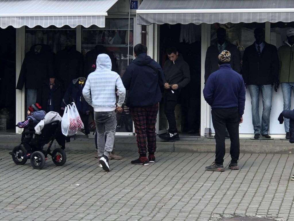 Люди біля крамниці з одягом та дитячий візок.