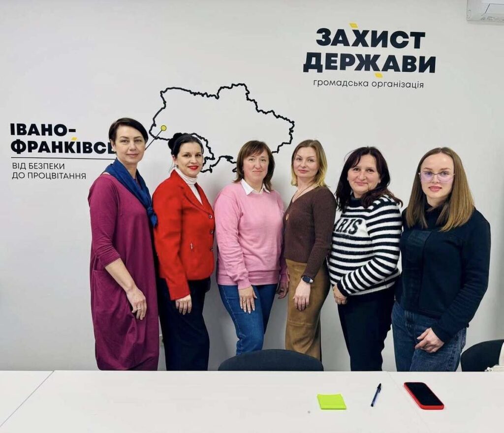 Шість жінок перед мапою України в офісі.