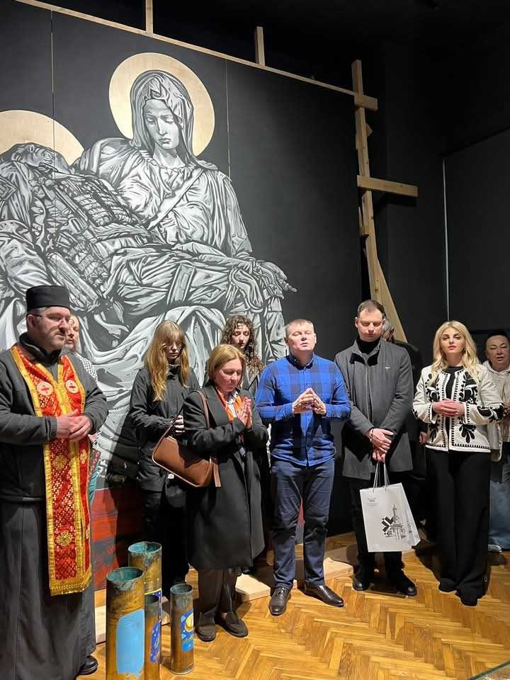 Люди моляться перед релігійним артом у галереї.