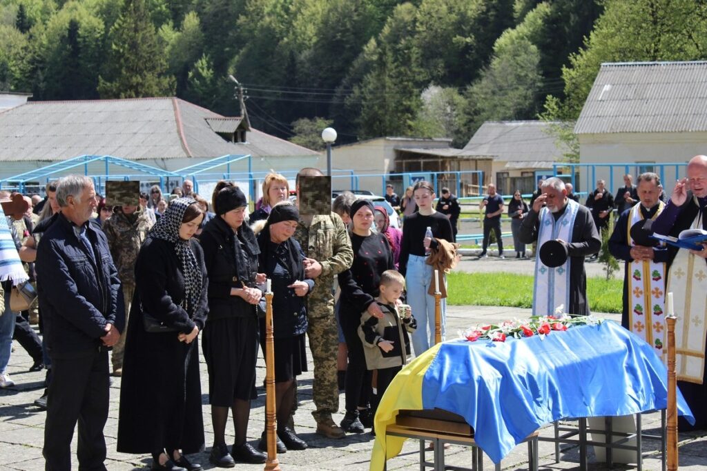 Похоронна церемонія з українським прапором на труні.