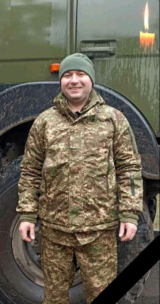 Солдат у камуфляжі стоїть перед військовою машиною