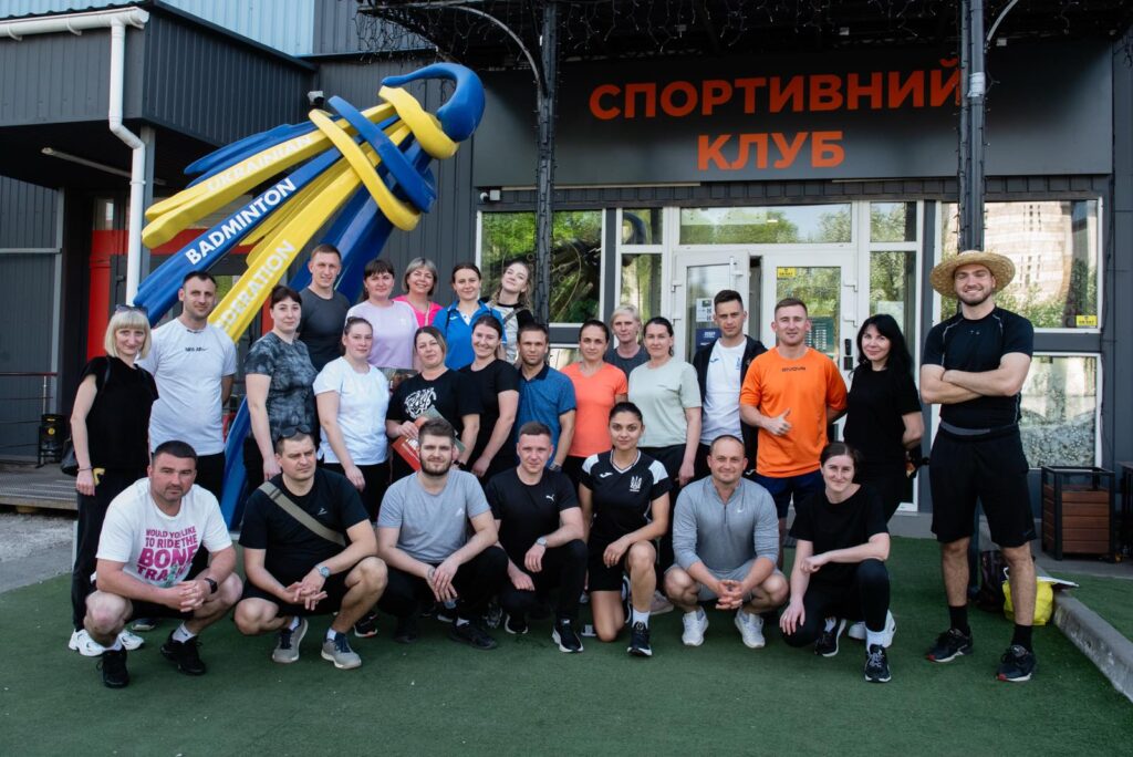 Група людей біля спортивного клубу з ракеткою.