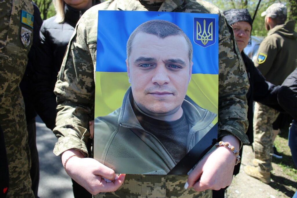 Військовий тримає фото на фоні прапора України.