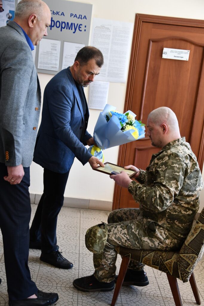 Вручають подяку і квіти військовому в камуфляжі.