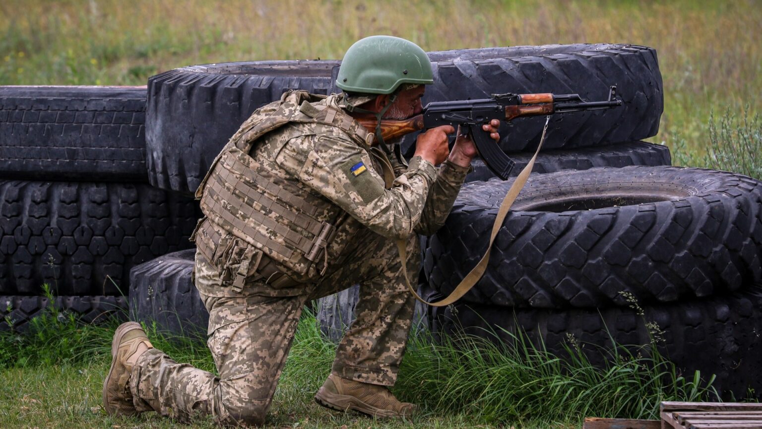 Військовий серед покришок, готується до стрільби.