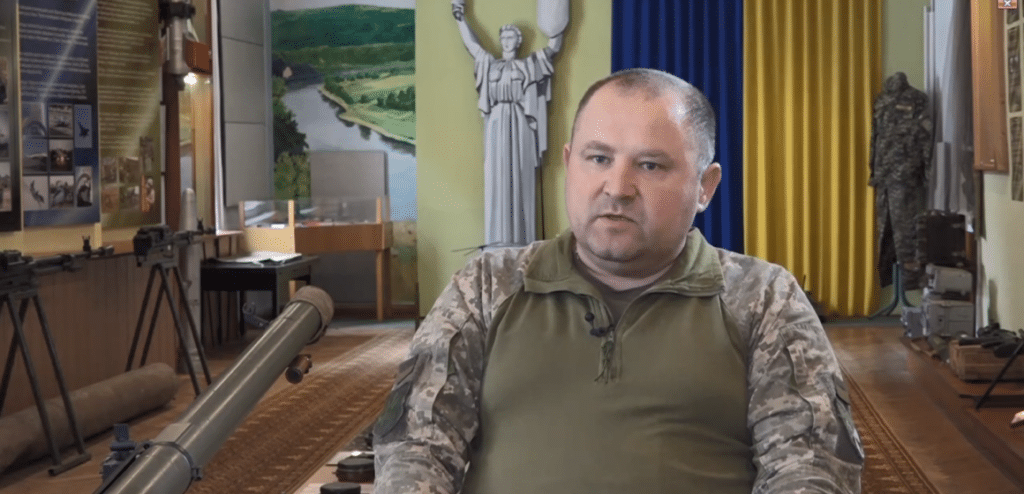 Чоловік у військовій формі в музеї з експонатами.