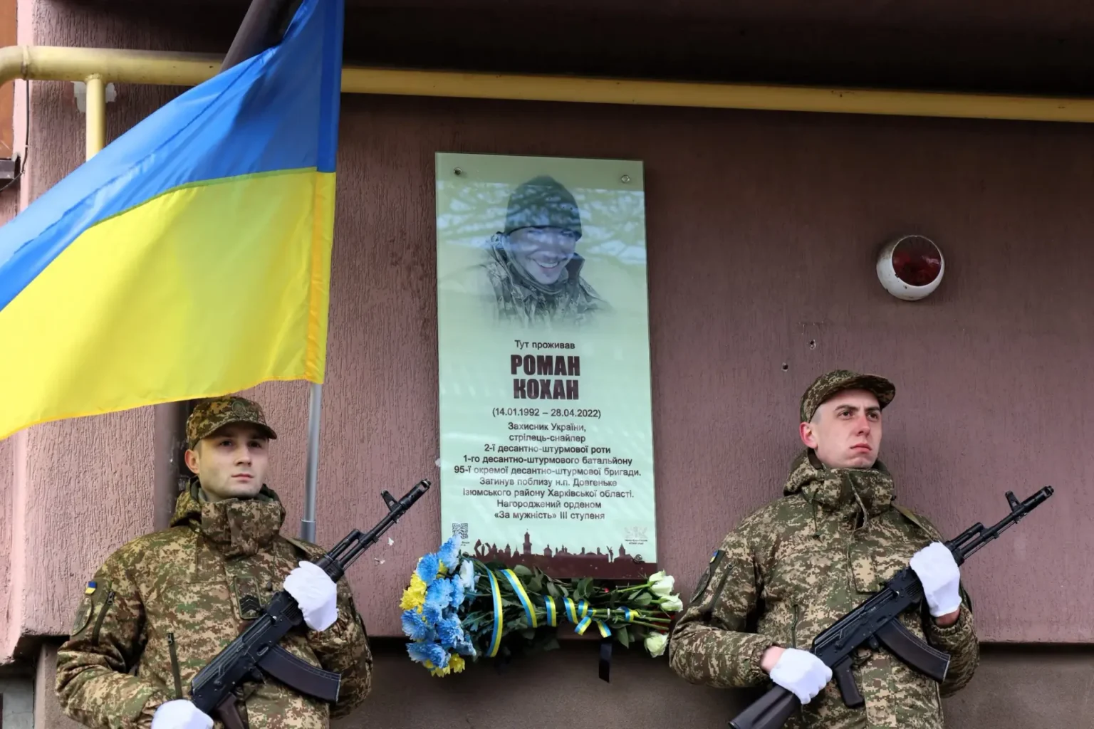 Українські солдати стоять біля пам'ятної дошки загиблому.