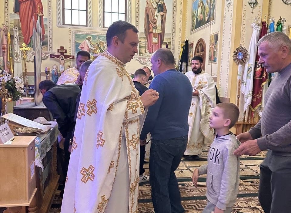 Священик причащає вірян у церкві.