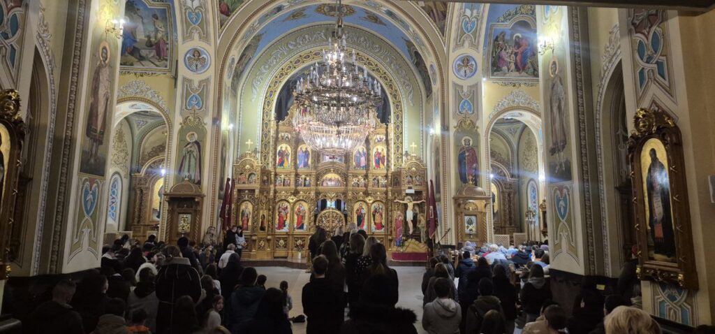 Інтер'єр української церкви з відвідувачами та іконами.