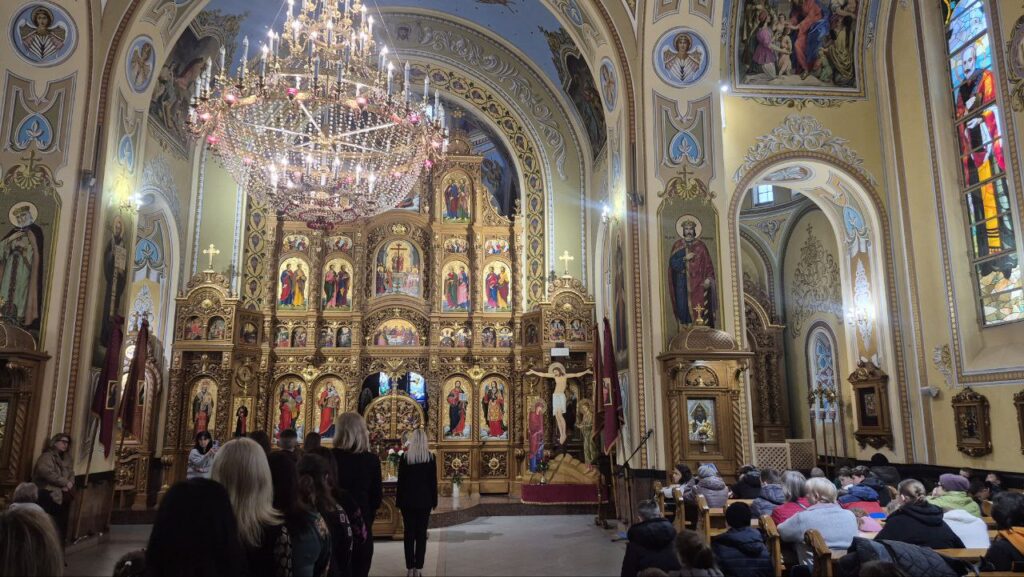 Інтер'єр церкви, золотий іконостас, люди у храмі