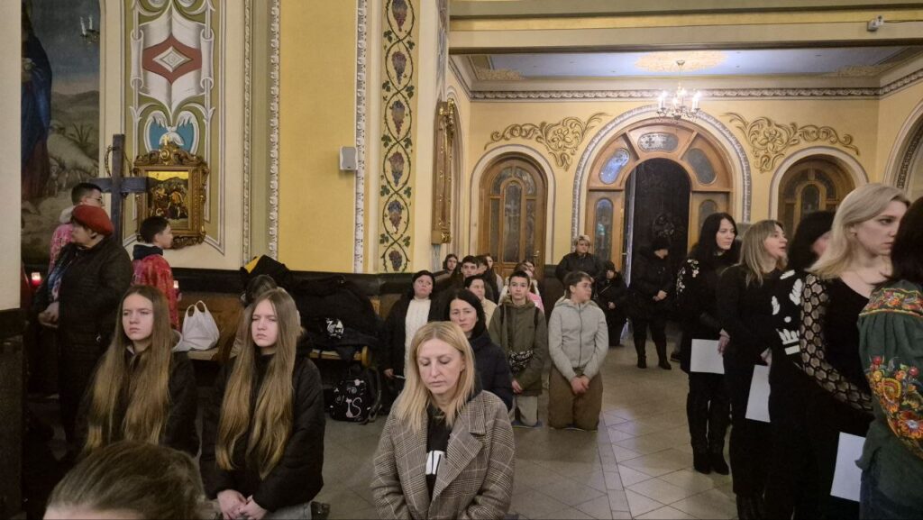 Люди моляться у церкві, інтер'єр декорований орнаментами.