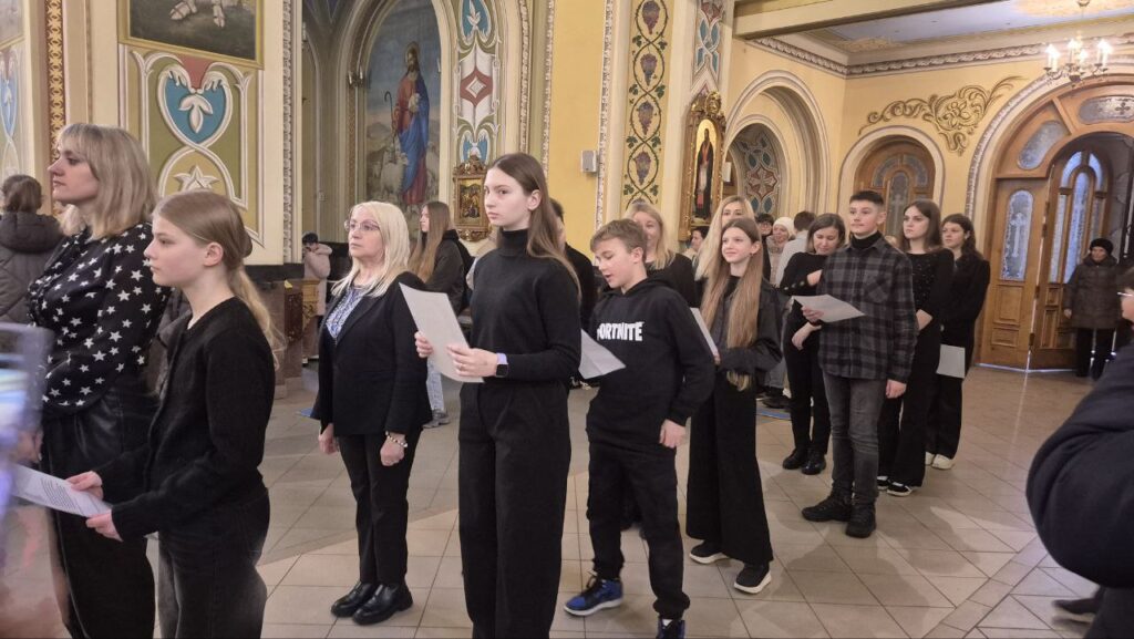 Люди в церкві стоять з аркушами паперу.