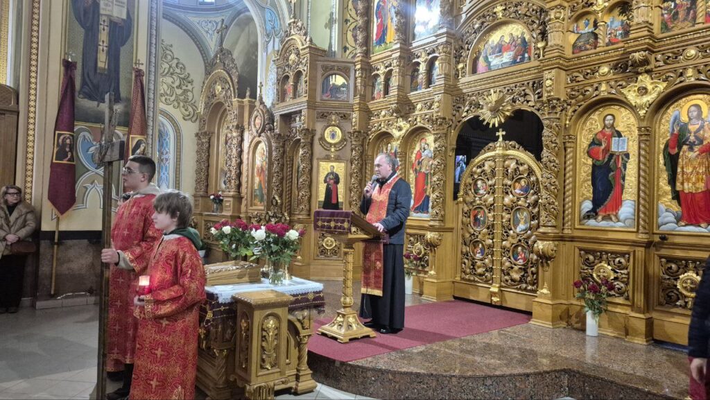 Священик у церкві проводить літургію біля іконостасу.