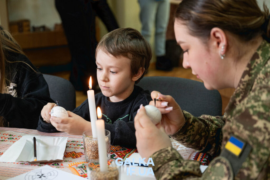 Дитина робить писанки під наглядом дорослого.