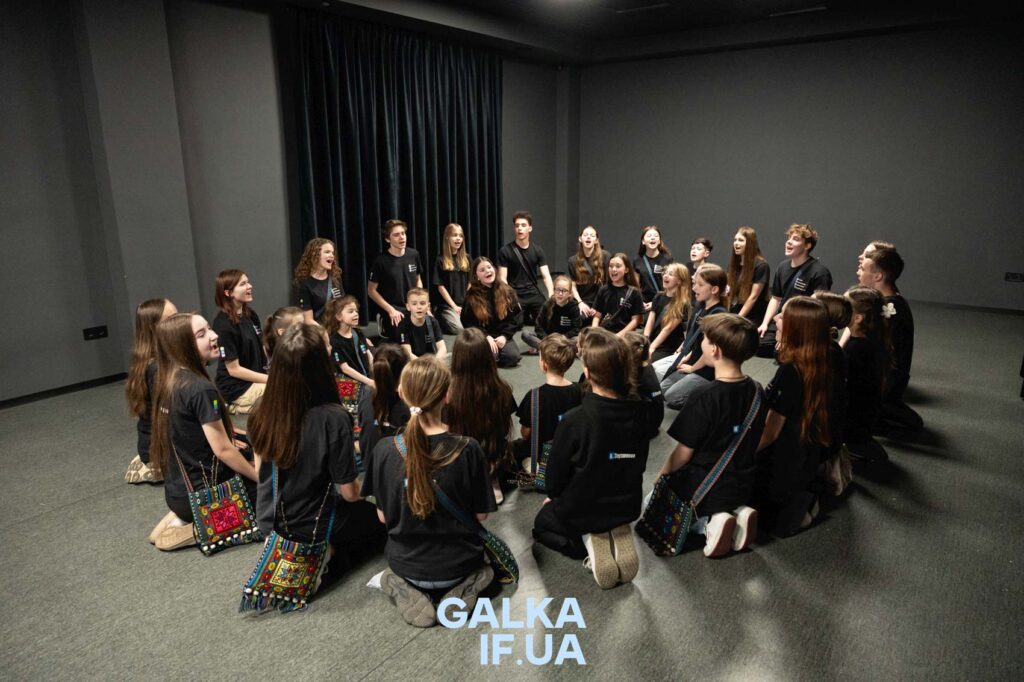 Група молоді співає в колі в кімнаті.