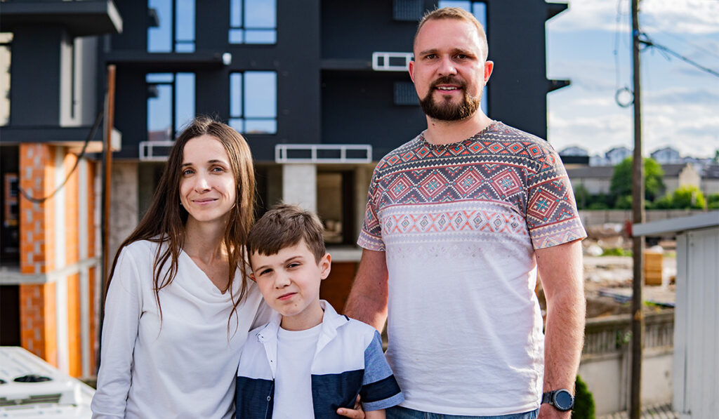 Сім'я перед новобудовою на фоні міста.