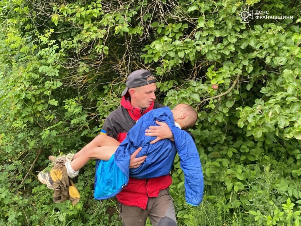 Рятувальник несе дитину серед лісу
