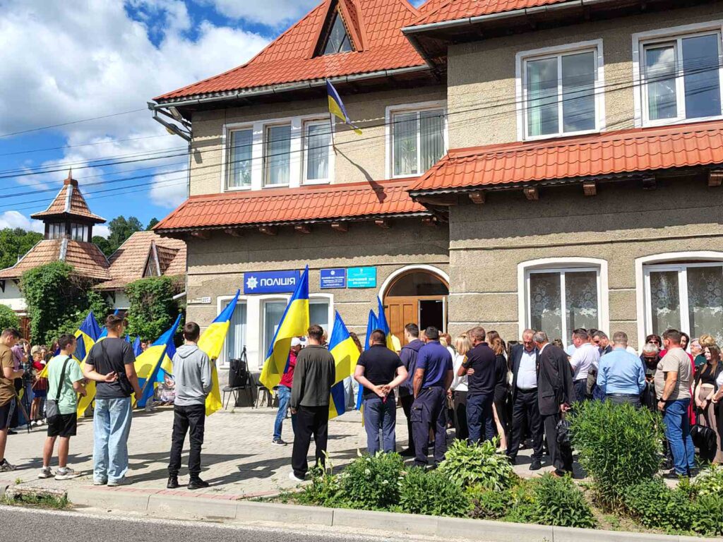 Люди збираються біля поліцейського відділку з прапорами України.